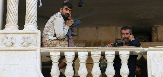 مقاتلان من «لواء صقور الجبل» الذي يقاتل تحت راية الجيش السوري الحر يجلسان على شرفة مقر اللواء بحلب. ر ويترز