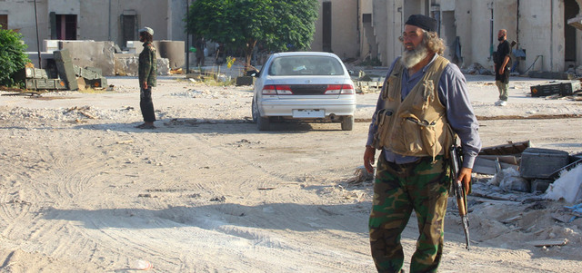 مقاتل من «جيش الفتح» يحمل سلاحه وسط قرية الزيارة التي سيطر عليها بريف حماة الغربي. رويترز