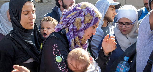 مهاجرون  سوريون ينتظرون الحافلة التي ستقلهم إلى المجر في قرية ميراتوفاك الصربية. رويترز