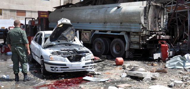 عسكري يتفقد الأضرار الناجمة عن سقوط قذيفة في محطة وقود بحي الإنشاءات بحمص. إي.بي.إيه