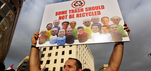 متظاهر لبناني يحمل ملصقاً تعبيرياً يربط الطبقة السياسية بأزمة النفايات.  أ.ب