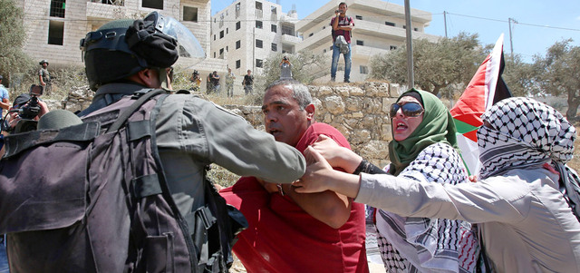 شرطي إسرائيلي خلال اعتقاله فلسطينياً في احتجاجات بيت جالا. إي.بي.إيه