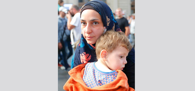 مهاجرة تحمل طفلتها أمام محطة القطار الرئيسة في بودابست بعد أن أخلت السلطات المجرية المحطة من المهاجرين.  رويترز