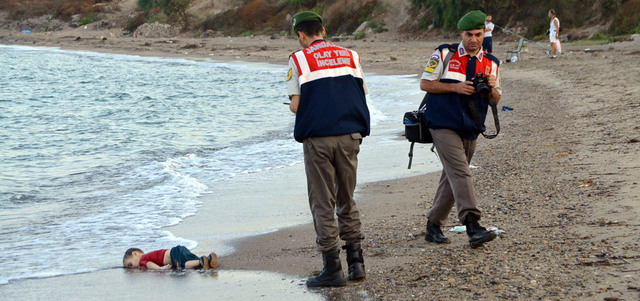 شرطيان تركيان أمام جثة طفل سوري غرق مقابل بلدة بودروم خلال محاولة للإبحار إلى جزيرة كوس اليونانية. إي.بي.إيه.  رويترز