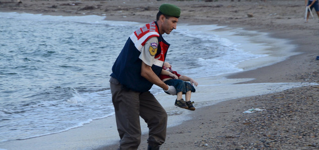 شرطي تركي يحمل جثة طفل سوري غرق مقابل بلدة  بودروم خلال محاولة  للإبحار إلى جزيرة كوس اليونانية. رويترز