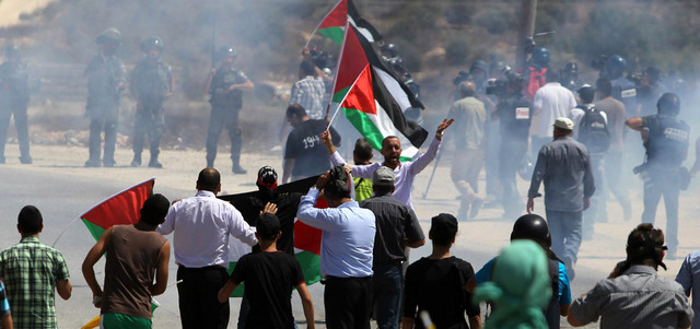 فلسطينيون يرفعون العلم خلال مواجهات مع الاحتلال في قرية النبي صالح قرب رام الله. أ.ف.ب