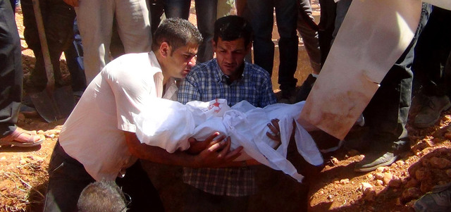 عبدالله شنو يحمل جثمان طفله آلان الذي قضى غرقاً خلال دفنه مع شقيقه ووالدته في مدينة عين العرب. أ.ف.ب