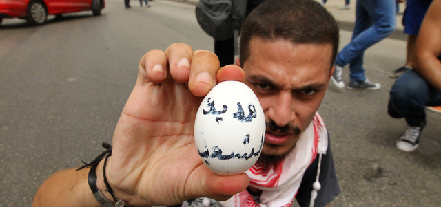 ناشط لبناني يحمل بيضة كتب عليها: «هدية من الشعب»، قبل رميها على موكب أحد السياسيين المشاركين في الحوار. أ.ف.ب