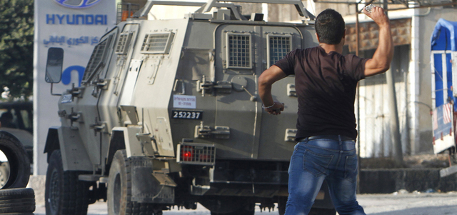 فلسطيني يرشق سيارة للاحتلال في نابلس. رويترز