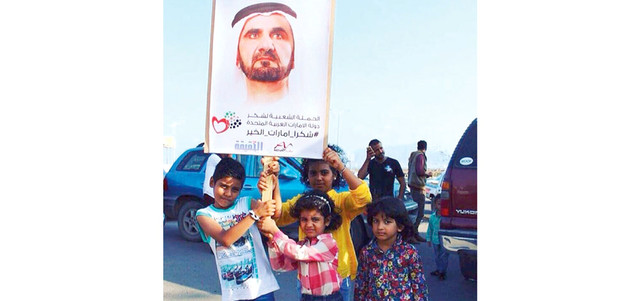 متظاهرون يرفعون صورة محمد بن راشد عرفاناً بدور الإمارات. وام