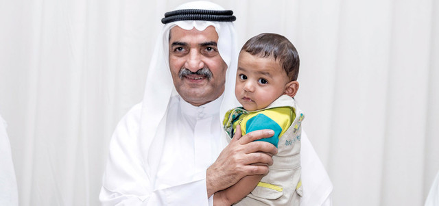 حاكم الفجيرة يحتضن طفلاً من ذوي الشهيد يوسف الكعبي.وام