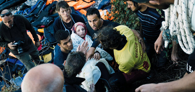 مسعفون ومتطوعون يحملون امرأة سورية  وضعت مولوداً على الشاطئ بعد وصولها إلى جزيرة ليسبوس اليونانية. أ.ف.ب