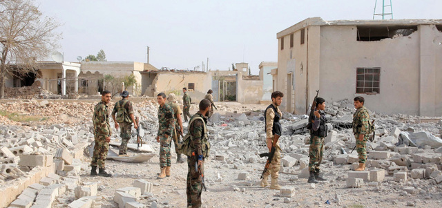 جنود من القوات النظامية أمام مبانٍ مدمرة في الضواحي الشرقية لمدينة حلب.   أ.ف.ب