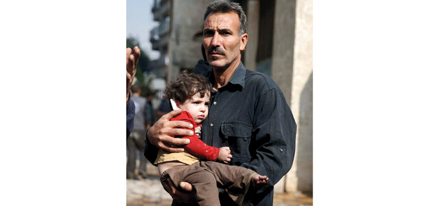 رجل يحمل طفلاً مصاباً بصواريخ أطلقتها القوات النظامية السورية على سوق مزدحمة في مدينة دوما بريف دمشق.   رويترز