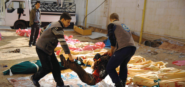 عمال إنقاذ يجمعون جثث قتلى القصف على مدينة دوما في أحد المراكز. أ.ف.ب