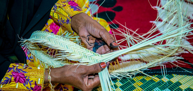 الحرفيات الإماراتيات يعملن على صناعة الخوص في ركن خاص بالمهرجان.  من المصدر