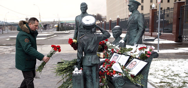 رجل يضع الزهور على نصب خارج مقر قيادة الأركان في موسكو وضعت فيه صور للطيار الروسي الذي قتل في سورية. أ.ب