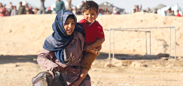صبية سورية تحمل شقيقها ضمن العالقين على الحدود الأردنية. إي.بي.إيه