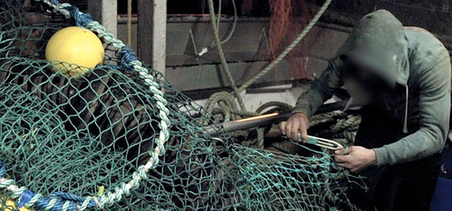 عامل صيد أجنبي يعمل على إصلاح الشباك دون أن يظهر وجهه أمام الكاميرا. أرشيفية