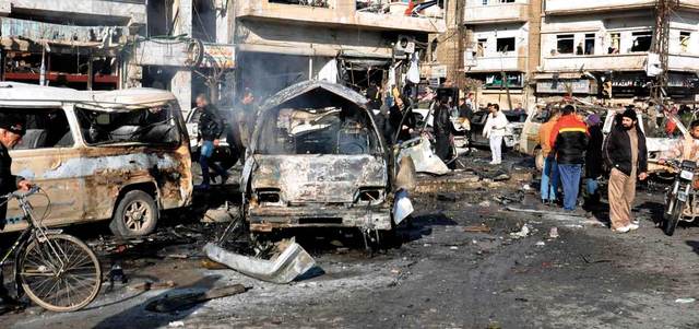 رجال الشرطة السورية ومدنيون يتفقدون موقع التفجيرين في الزهراء بحمص.  إي.بي.إيه