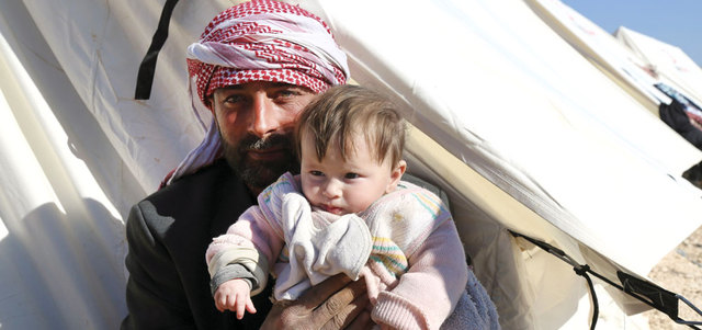 رجل يحمل طفلاً في مخيم مؤقت للنازحين قرب معبر باب السلامة الحدودي مع تركيا.

أ.ب