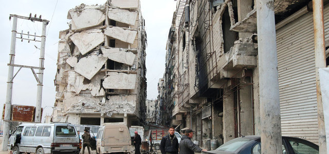 سوريون أمام مبانٍ مهدمة ومتضررة في حلب بسبب قصف القوات السورية لأحياء المدينة.     أ.ب