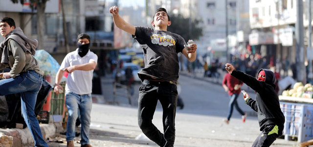 فلسطينيون خلال المواجهات مع قوات الاحتلال في الخليل.  إي.بي.إيه