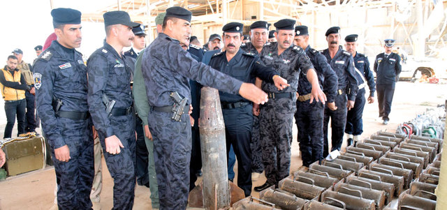 ضباط شرطة يتفقدون الأسلحة والإمدادات المصادرة من «داعش» في الرمادي.   إي.بي.إيه