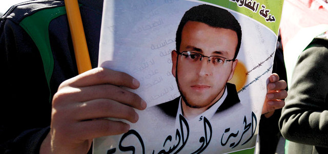 فلسطيني يحمل صورة الأسير محمد القيق خلال احتجاج في رام الله. رويترز