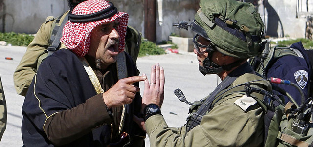 فلسطيني في مواجهة مع جندي إسرائيلي بالقرب من الخليل. رويترز