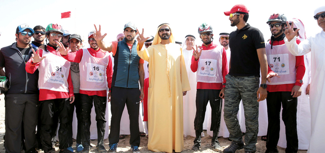 محمد بن راشد يشهر علامة النصر خلال متابعته لبطولة كأس الخليج الأولى للقدرة بحضور حمدان بن محمد. وام