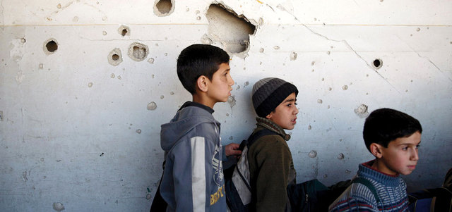 أطفال سوريون يقفون داخل مدرستهم المتضررة في مدينة دوما الخاضعة لسيطرة المعارضة في ريف دمشق. رويترز