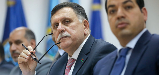 فايز السراج (وسط) خلال اجتماعه مع فريقه الحكومي في طرابلس.  أ.ب