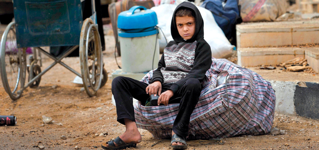صبي سوري ينتظر مع عائلته حافلة لتقلّهم إلى تدمر بعد استعادتها من «داعش».    أ.ب