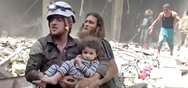 رجل إسعاف ينقذ طفلاً بعد غارات النظام السوري على مدينة حلب.

أ.ب