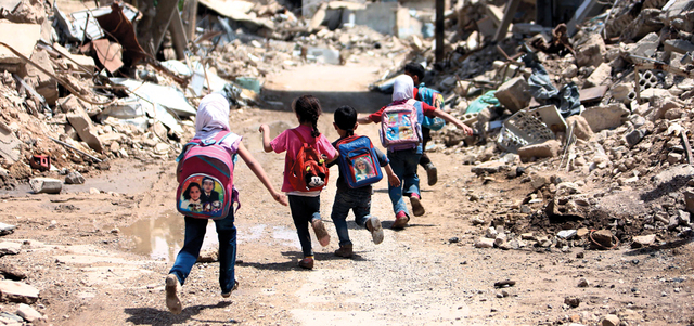 أطفال يسيرون بين أنقاض المباني في طريقهم إلى المدرسة بحي جوبر على مشارف دمشق. أ.ف.ب