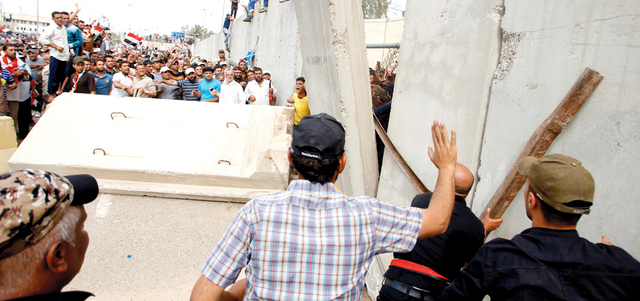 متظاهرون غاضبون لحظة اقتحامهم أسوار المنطقة الخضراء المحصّنة وسط بغداد.  رويترز