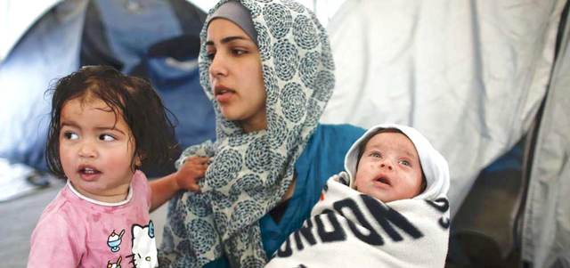 لاجئة سورية تحمل ابنها البالغ من العمر 40 يوماً.. وبجانبها طفلتها في مخيم مؤقت بالقرب من قرية إيدوميني على الحدود اليونانية ــ المقدونية. رويترز