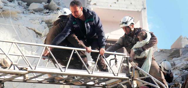 أعضاء من الدفاع المدني يخلون طفلاً من تحت أنقاض مبنى تهدم بغارة روسية على إدلب. أ.ف.ب