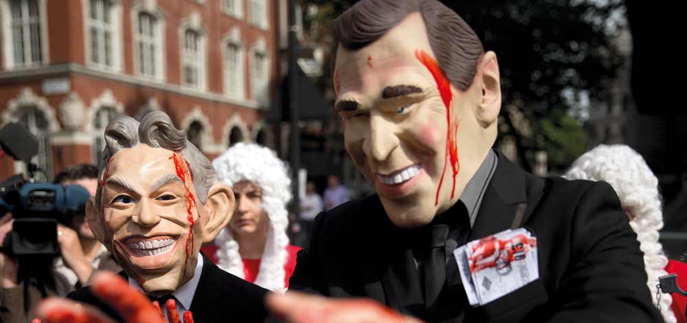 متظاهرون غطوا وجوههم بأقنعة تجسد وجهي بلير وبوش ملطخة بالدماء. ا.ب