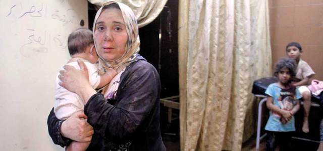 امرأة تحمل طفلها داخل مستشفى مؤقت في أعقاب قصف لقوات النظام على مدينة إدلب. أ.ف.ب