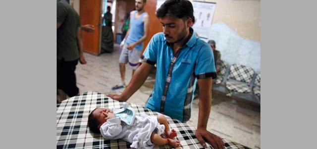 رجل  ينظر إلى رضيع يتلقى العلاج في مستشفى ميداني بعد إصابته بقصف لقوات النظام على مدينة دوما بريف دمشق. أ.ف.ب