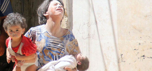 سورية تحمل طفليها بعد غارات للنظام على مدينة إدلب. أ.ف.ب