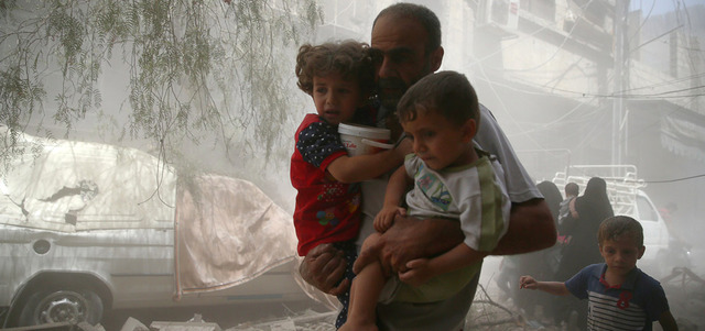 رجل يحمل طفلين ويبعدهما عن مكان استهدفته غارة جوية لقوات النظام في مدينة دوما بريف دمشق. رويترز