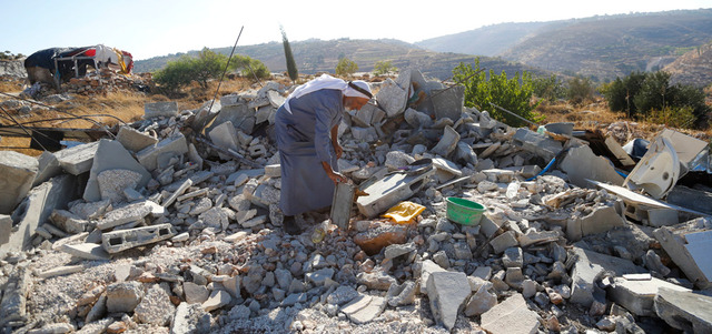 فلسطيني على أنقاض منزل دمرته قوات الاحتلال قرب الخليل. أ.ب