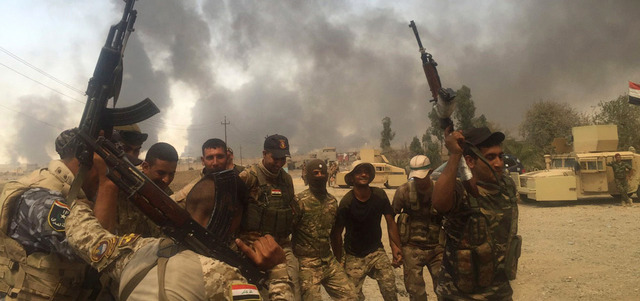 عناصر أمن عراقيون يحتفلون بتحرير القيارة من «داعش». أ.ب