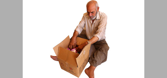 عجوز سوري يبدو حزيناً وهو يتفحص صندوقاً يحوي بعض المواد التموينية التي لم يحصل على شيء منها وهو في داريا المحاصرة. أ.ف.ب