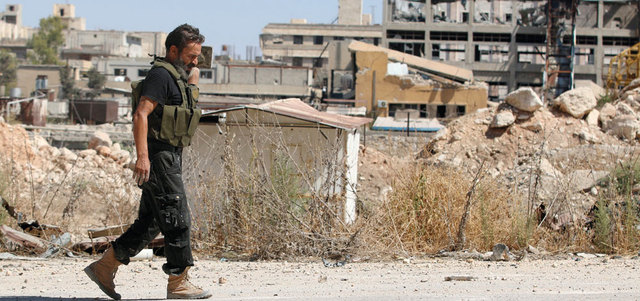 مقاتل من المعارضة يمشي بين المباني المدمرة قرب طريق الكاستيلو في حلب. رويترز