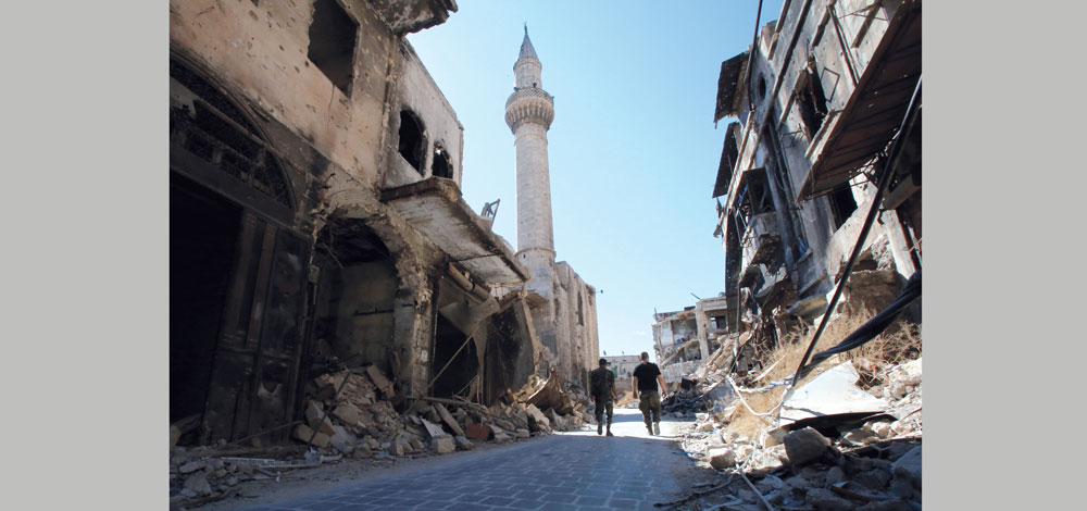 جنود من القوات النظامية يدخلون إلى سوق الفرافرة التاريخي المتضرر في مركز مدينة حلب القديمة. أ.ف.ب