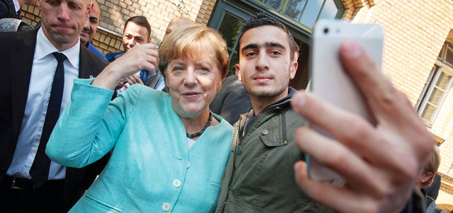 ميركل تلتقط «سيلفي» مع أحد المهاجرين الذين تعاطفت معهم وسمحت لهم بدخول ألمانيا دون تحديد لعددهم. أرشيفية